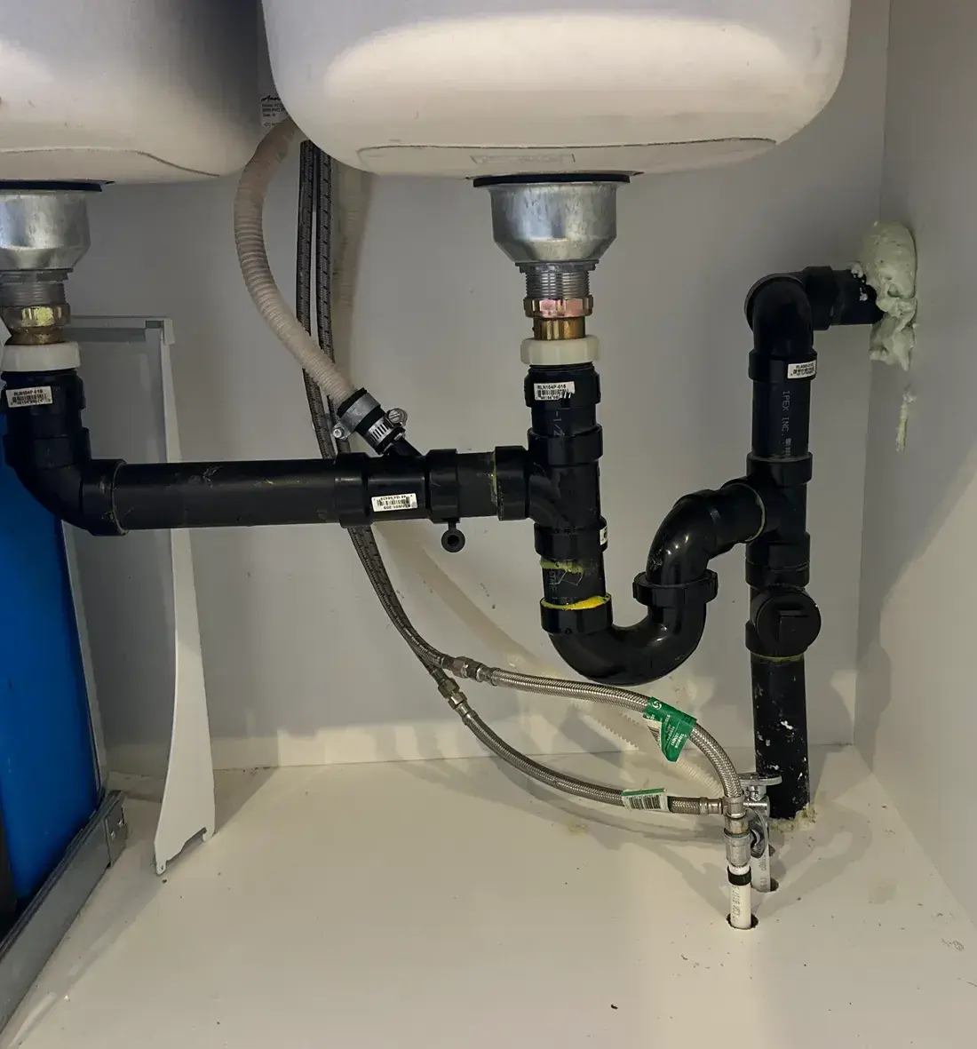 Freshly plumbed double-bowl sink drain assembly with P-trap and dishwasher hose