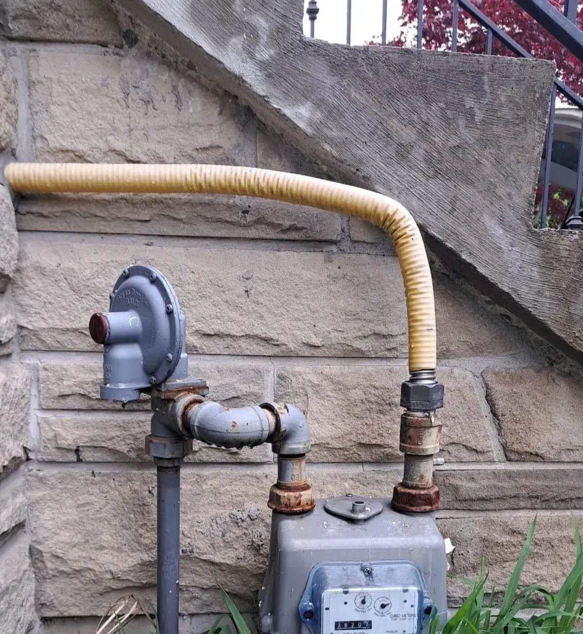 Gas meter with a new flex connector on a stone wall