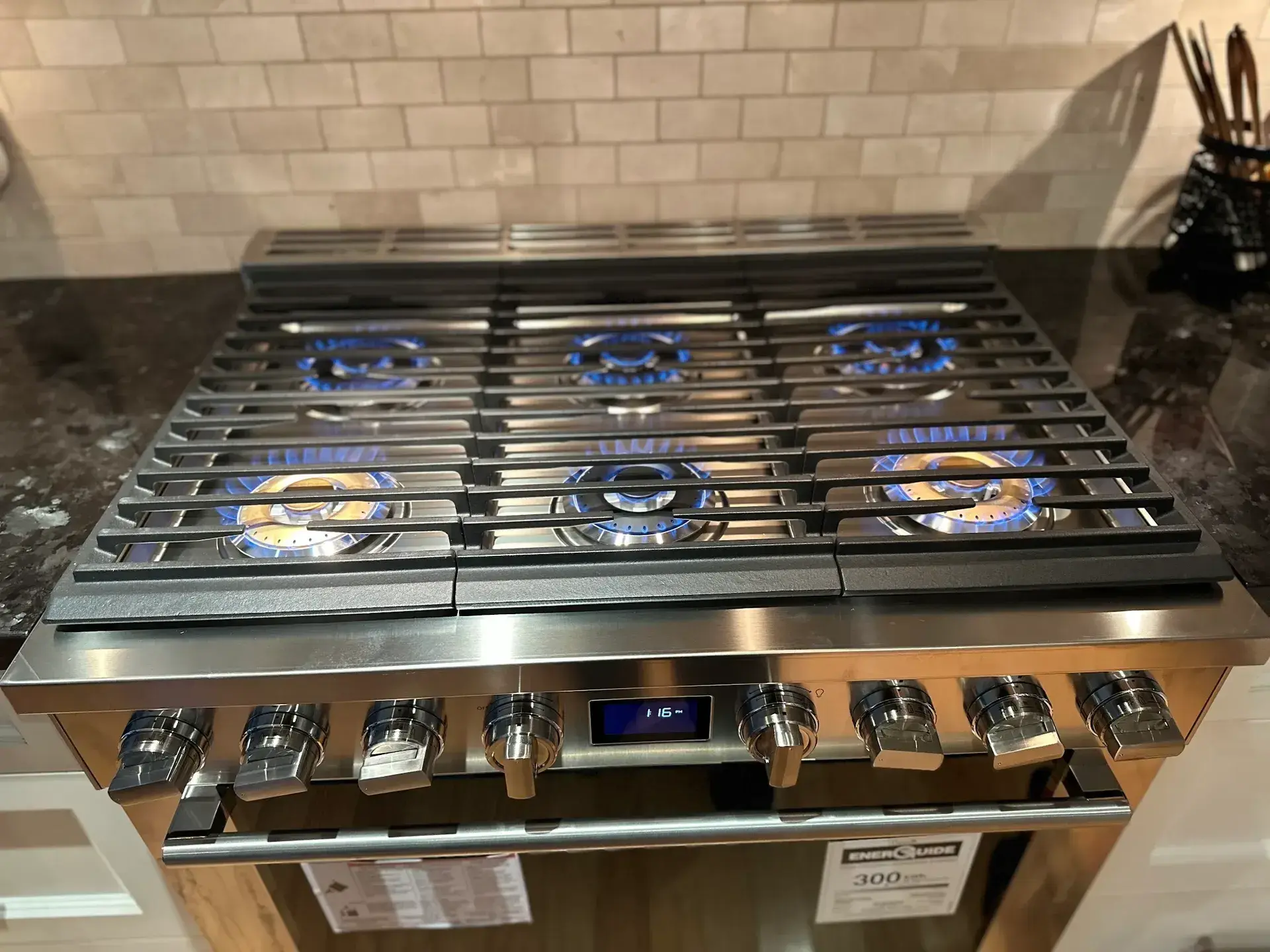 Six burners lit blue on a professional gas range installed by Smood Services