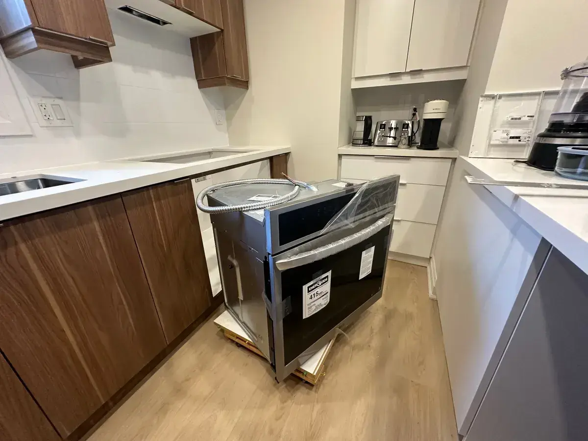 Appliance being installed in a walnut and white kitchen