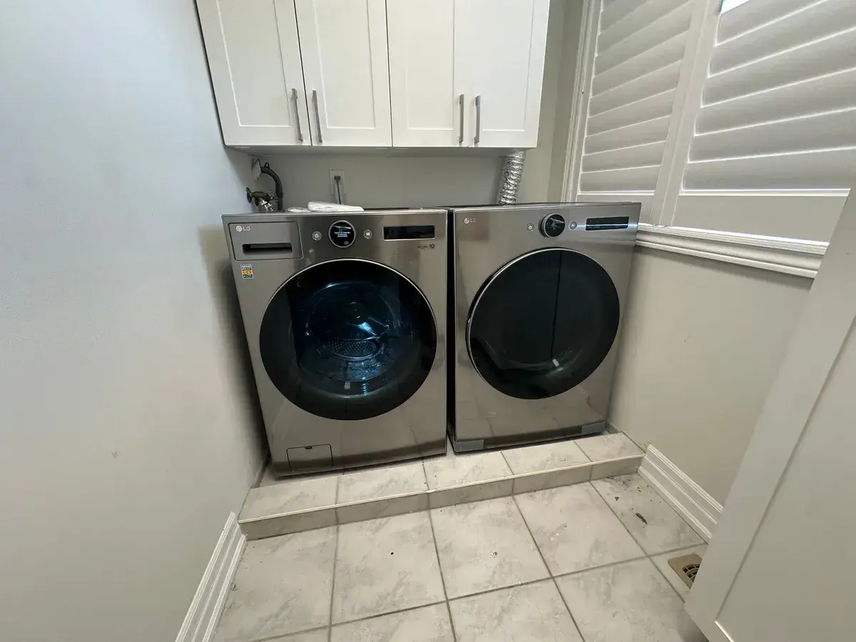 Washer and dryer pair in a fitted white laundry room