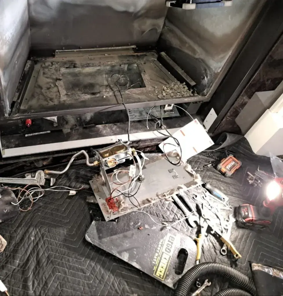 Appliance pulled out mid-repair, tools and work light on a drop mat