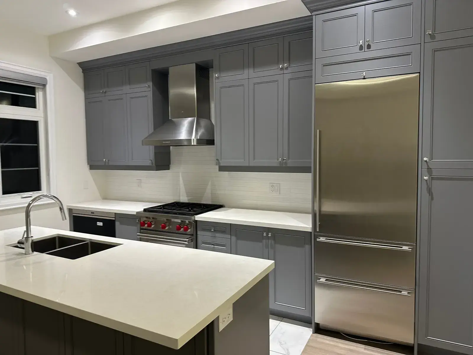 Finished grey kitchen with Wolf rangetop, chimney hood and panel-ready refrigeration