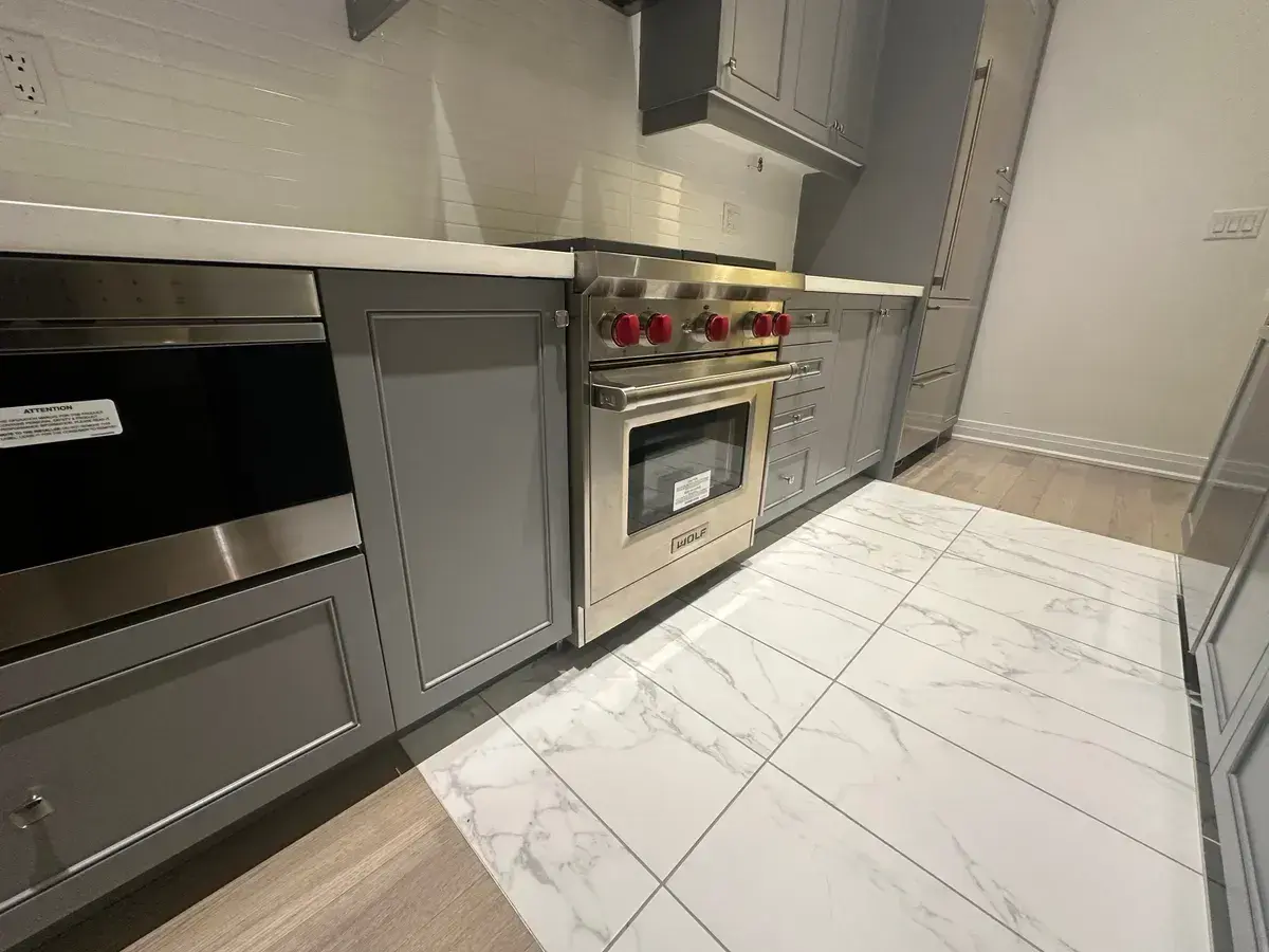 Wolf gas range with red knobs installed in a grey shaker kitchen